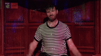 A Man Is Dancing In Front Of A Bbc Live Sign GIF