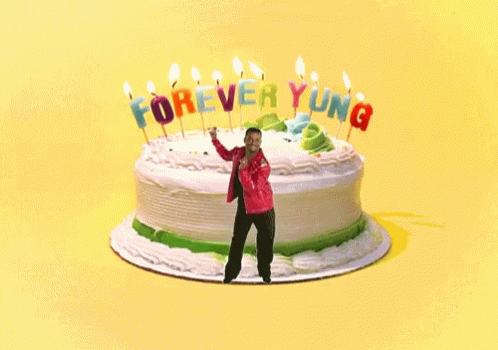 A Man Is Dancing In Front Of A Birthday Cake That Says Forever Young GIF