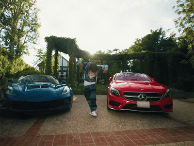 A Man Is Dancing In Front Of A Blue Car And A Red Mercedes GIF
