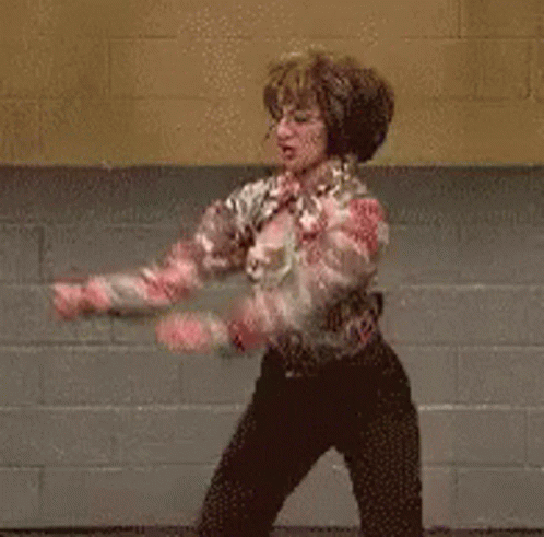 A Man Is Dancing In Front Of A Brick Wall . GIF