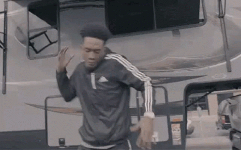 A Man Is Dancing In Front Of A Camper Van . GIF