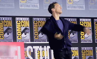 A Man Is Dancing In Front Of A Comic Con Banner GIF
