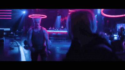 A Man Is Dancing In Front Of A Crowd In A Club With Purple And Blue Lights . GIF