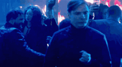 A Man Is Dancing In Front Of A Crowd Of People In A Club . GIF