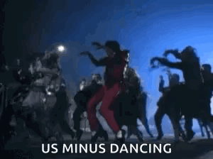 A Man Is Dancing In Front Of A Crowd Of People With The Words `` Us Minus Dancing '' Written Below Him . GIF