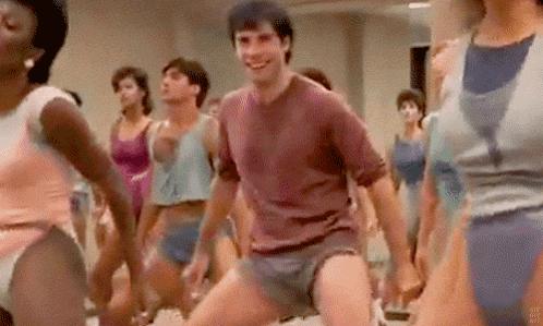 A Man Is Dancing In Front Of A Group Of People In A Gym . GIF