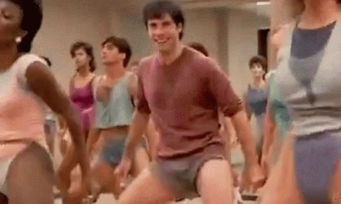 A Man Is Dancing In Front Of A Group Of Women In A Gym . GIF