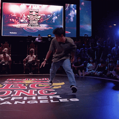 A Man Is Dancing In Front Of A Large Screen That Says Red Bull Bc One GIF