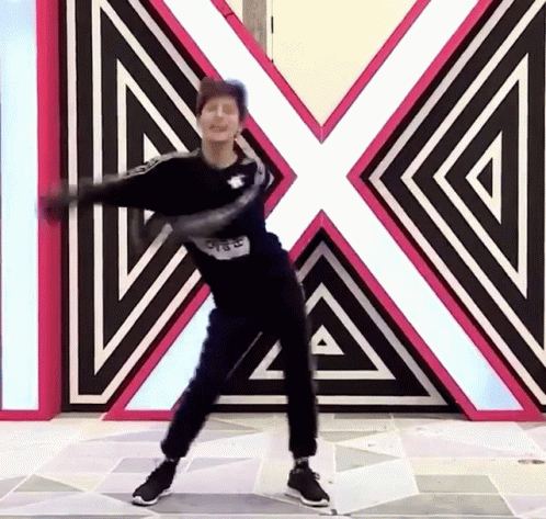 A Man Is Dancing In Front Of A Large X On The Wall GIF