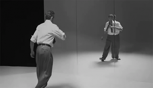 A Man Is Dancing In Front Of A Mirror GIF