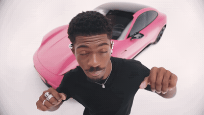 A Man Is Dancing In Front Of A Pink Sports Car GIF