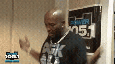 A Man Is Dancing In Front Of A Sign That Says Power 105.1 GIF