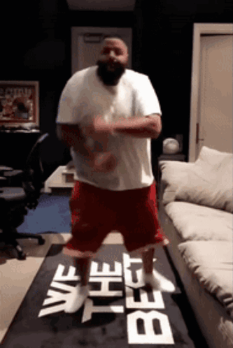 A Man Is Dancing In Front Of A Sign That Says " We Are The Best " GIF