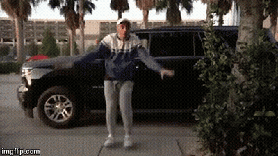 A Man Is Dancing In Front Of A Suv . GIF