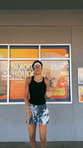 A Man Is Dancing In Front Of A Window That Says ' Cookie House ' On It GIF