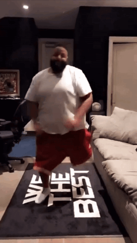 A Man Is Dancing On A Rug That Says " We The Best " GIF