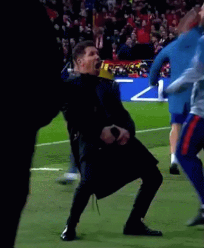 A Man Is Dancing On A Soccer Field While Holding A Microphone In His Hand . GIF
