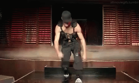 A Man Is Dancing On A Stage In A Dark Room With Shutters Behind Him . GIF