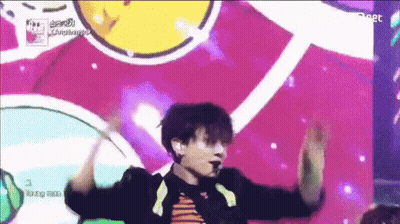 A Man Is Dancing On A Stage In Front Of A Colorful Background With The Word Compliments Written On It GIF