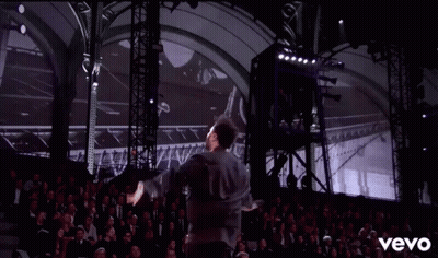 A Man Is Dancing On A Stage In Front Of A Crowd And The Word Vevo Is On The Bottom Of The Screen GIF