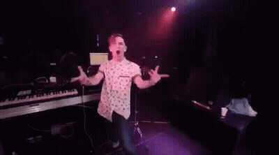 A Man Is Dancing On A Stage In Front Of A Crowd In A Club . GIF