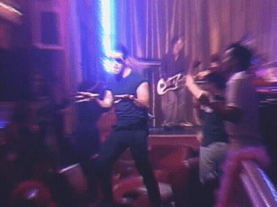 A Man Is Dancing On A Stage In Front Of A Group Of People Playing Instruments GIF
