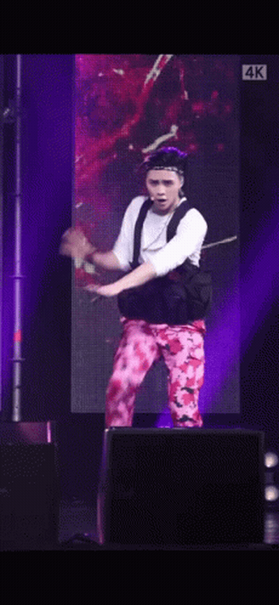 A Man Is Dancing On A Stage In Front Of A Large Screen . GIF