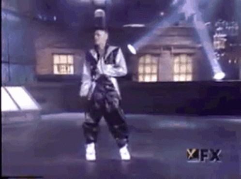 A Man Is Dancing On A Stage In Front Of A Sign That Says Fx GIF