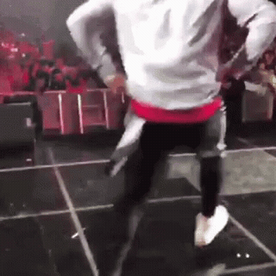 A Man Is Dancing On A Stage With A Crowd Watching . GIF