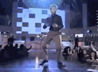 A Man Is Dancing On A Stage With A Crowd Watching GIF