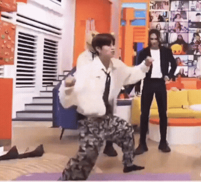 A Man Is Dancing On A Yoga Mat In A Living Room While A Man Stands Behind Him . GIF