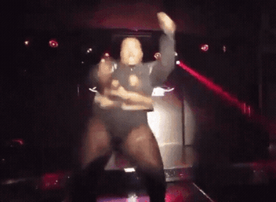 A Man Is Dancing On Stage In A Dark Room GIF
