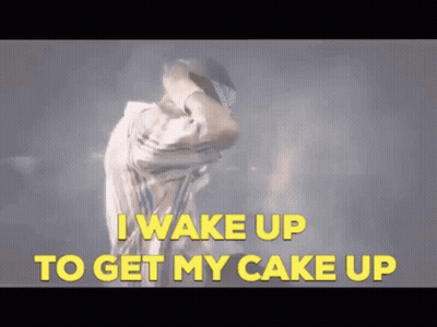 A Man Is Dancing With The Words " I Wake Up To Get My Cake Up " Behind Him GIF