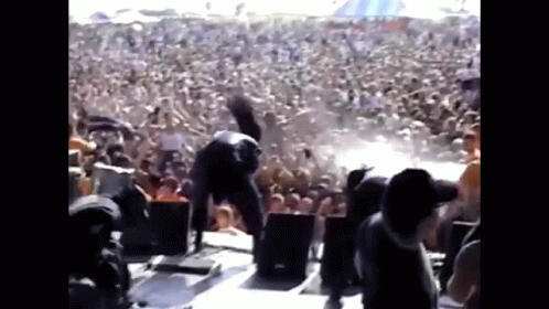 A Man Is Doing A Handstand In Front Of A Crowd At A Concert . GIF