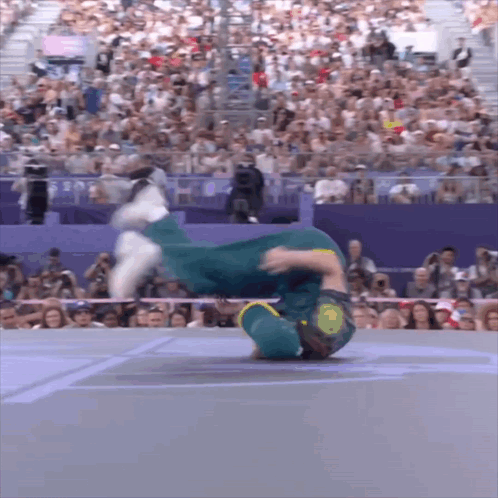 A Man Is Doing A Handstand In Front Of A Crowd That Is Watching GIF