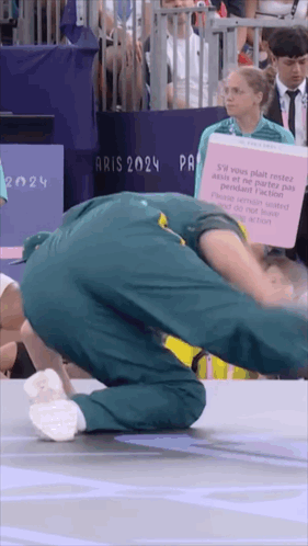 A Man Is Doing A Handstand In Front Of A Sign That Says " Aris 2024 " GIF