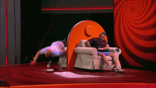 A Man Is Doing A Handstand In Front Of An Orange Chair GIF