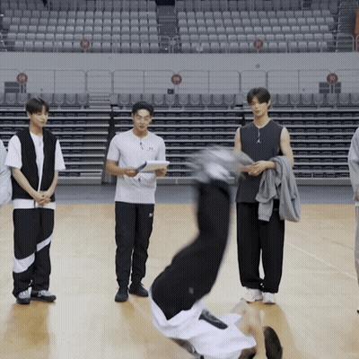 A Man Is Doing A Handstand On A Basketball Court In Front Of Empty Seats GIF