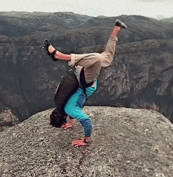 A Man Is Doing A Handstand On A Rocky Cliff . GIF