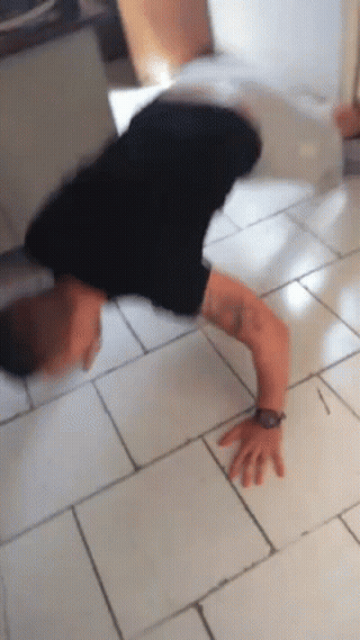 A Man Is Doing A Handstand On A Tile Floor GIF