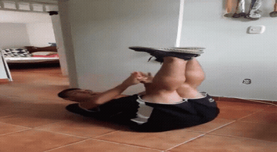 A Man Is Doing A Handstand On A Tile Floor In A Room . GIF