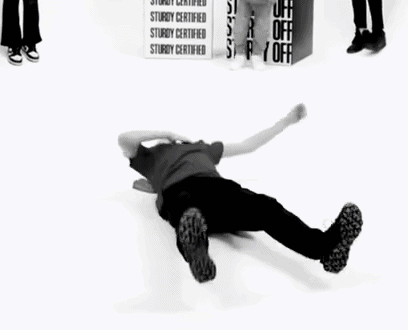 A Man Is Doing A Handstand On The Floor In Front Of A Group Of People . GIF
