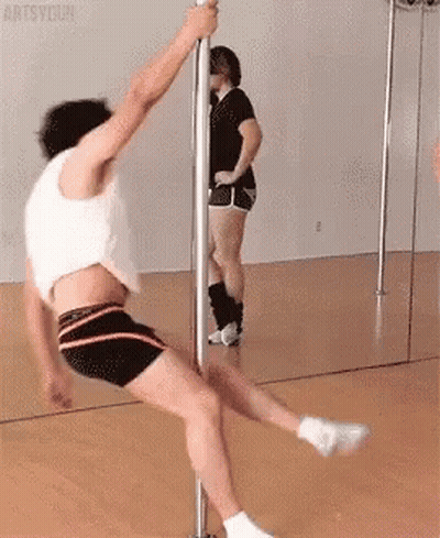 A Man Is Doing A Pole Dance In Front Of A Mirror While A Woman Watches . GIF