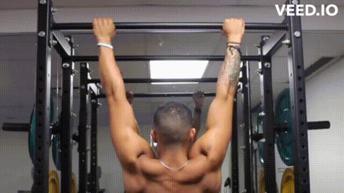 A Man Is Doing A Pull Up In A Gym . GIF