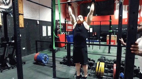A Man Is Doing A Pull Up In A Gym With A Sign On The Wall That Says ' Sport ' GIF