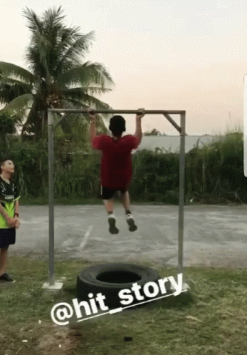 A Man Is Doing A Pull Up In Front Of A Tire And A Sign That Says @Hit_story GIF