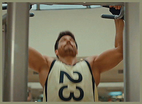 A Man Is Doing A Pull Up While Wearing A Jersey With The Number 23 On It GIF