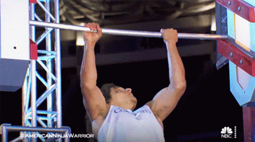 A Man Is Doing A Pull Up While Wearing A White Tank Top That Says Calvin Klein GIF