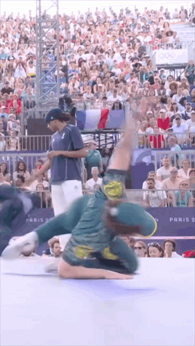 A Man Is Doing A Trick In Front Of A Crowd With A Sign That Says Paris 2 GIF