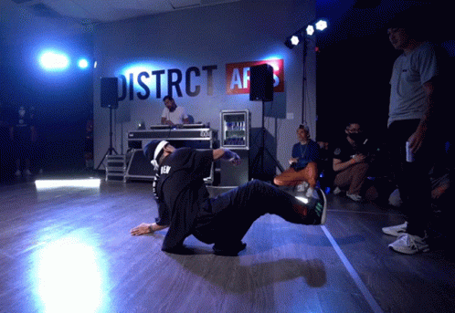 A Man Is Doing A Trick In Front Of A Sign That Says District Afs GIF